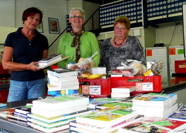 Bild: Ehrenamtliche Tafelmitarbeiterinnen vor der Ausgabe der Lebensmittelkisten und Buchspenden  von links: Margret Walzel, Elvira Dalitz und Margit Müller